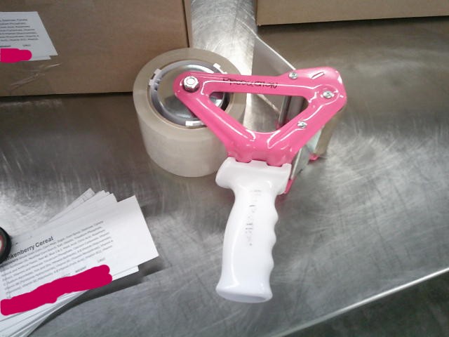Tape gun next to labels and in front of two boxes.